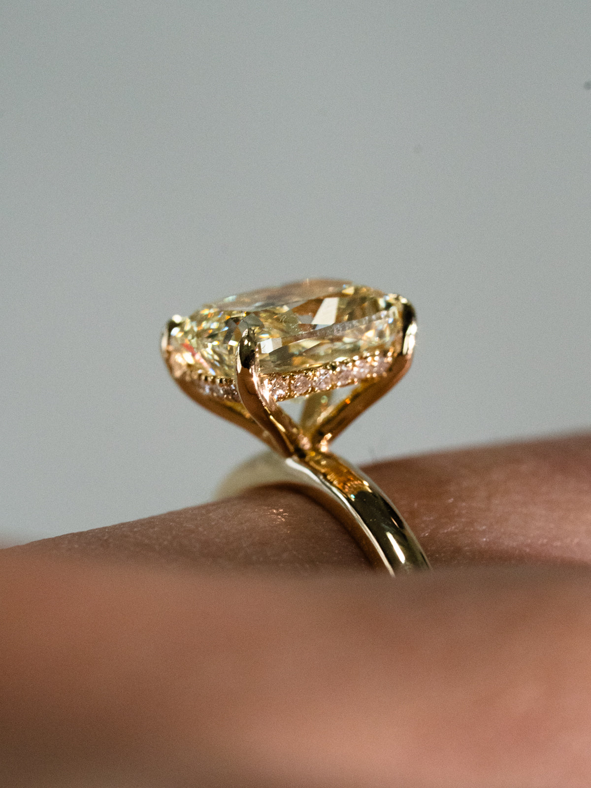 Fancy yellow elongated cushion cut diamond solitaire engagement ring with hidden halo in 18ct yellow gold - custom engagement ring on finger