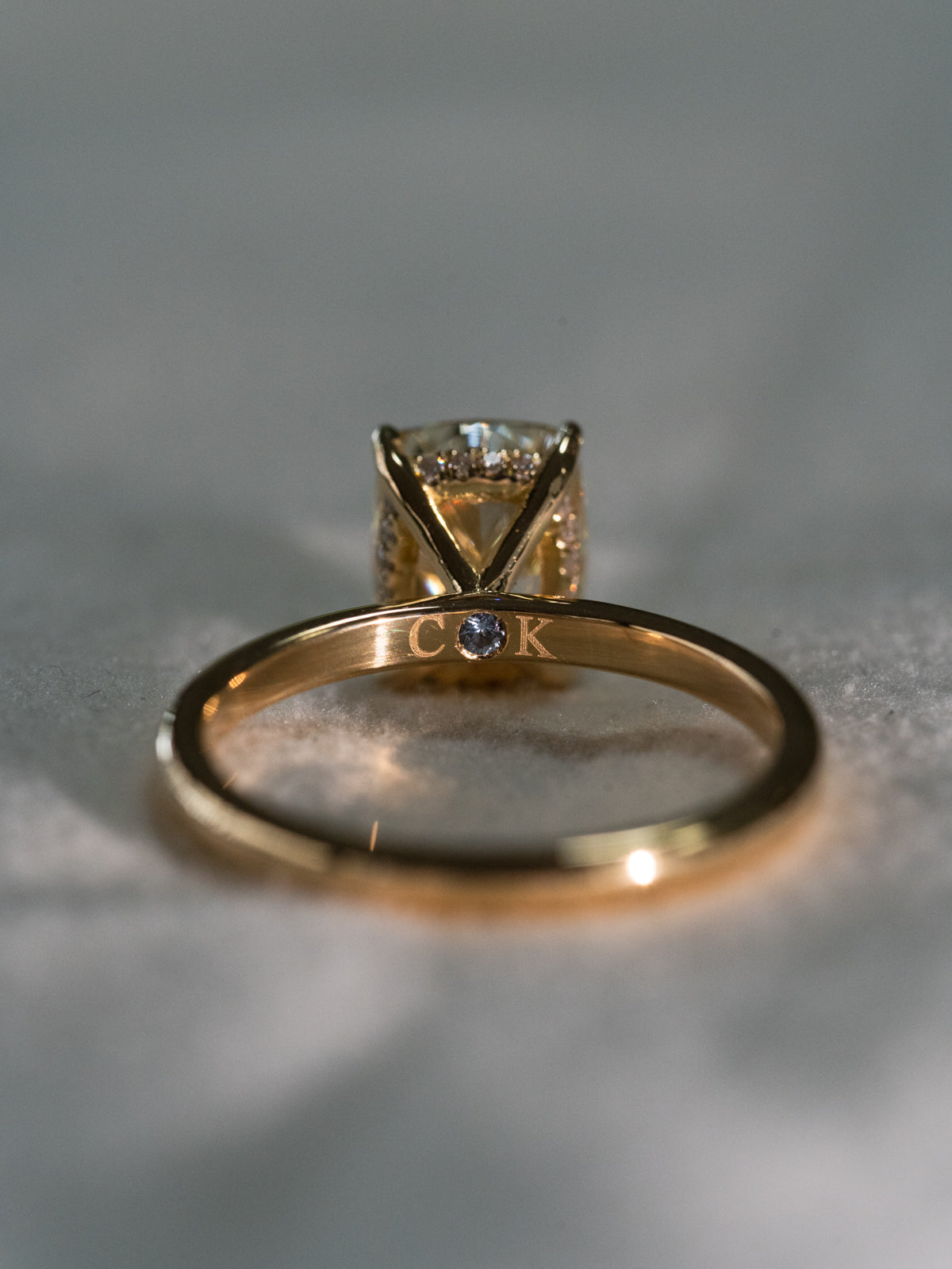 Custom engagement ring interior showing personalised engraving and hidden aquamarine birthstone in 18ct yellow gold band - bespoke engagement ring details