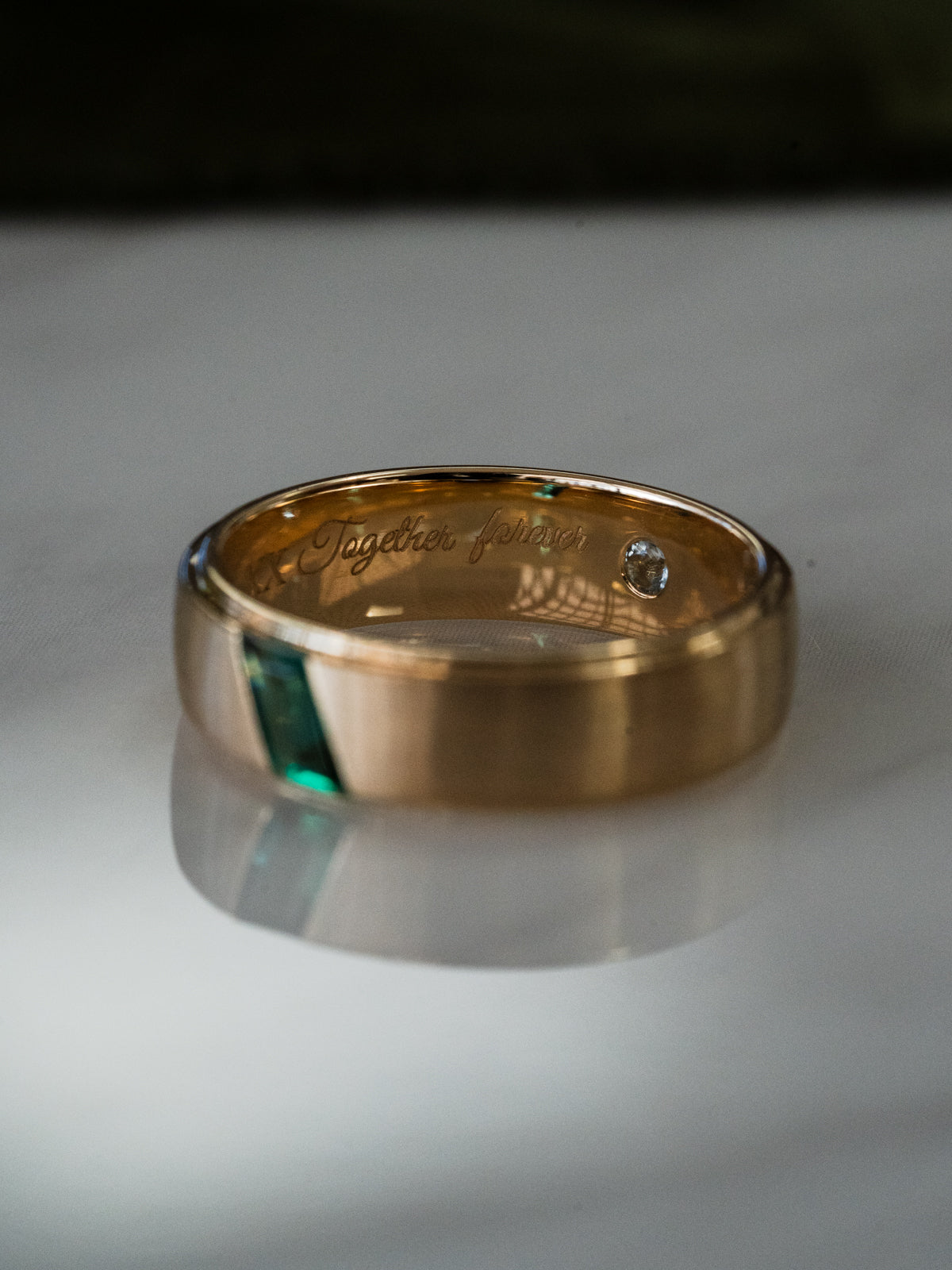 Modern gold wedding band with green emerald inlay and satin brushed finish