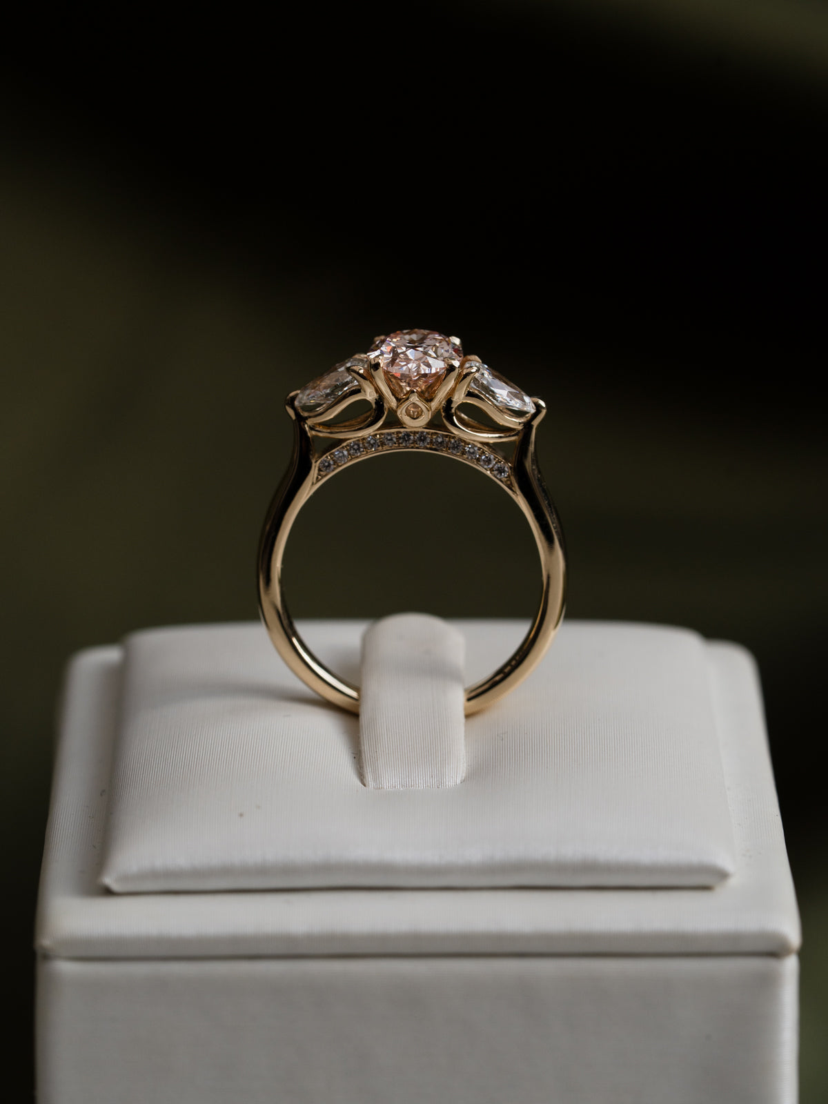 Rose gold ring with a diamond on a white cushion against a dark background