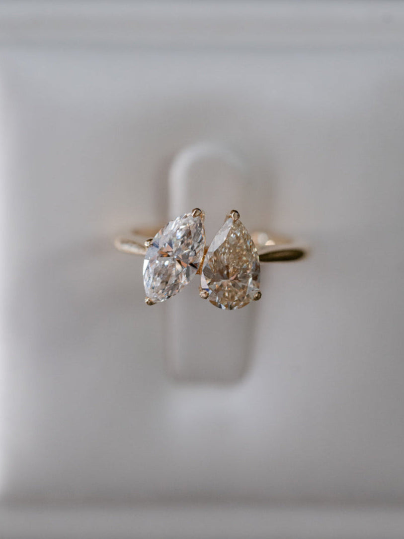 A stunning Toi et Moi engagement ring in yellow gold, featuring a harmonious pairing of a warm yellow pear-cut diamond and a brilliant white marquise-cut diamond. The asymmetrical yet balanced design symbolises two unique souls coming together, creating a timeless and meaningful piece.