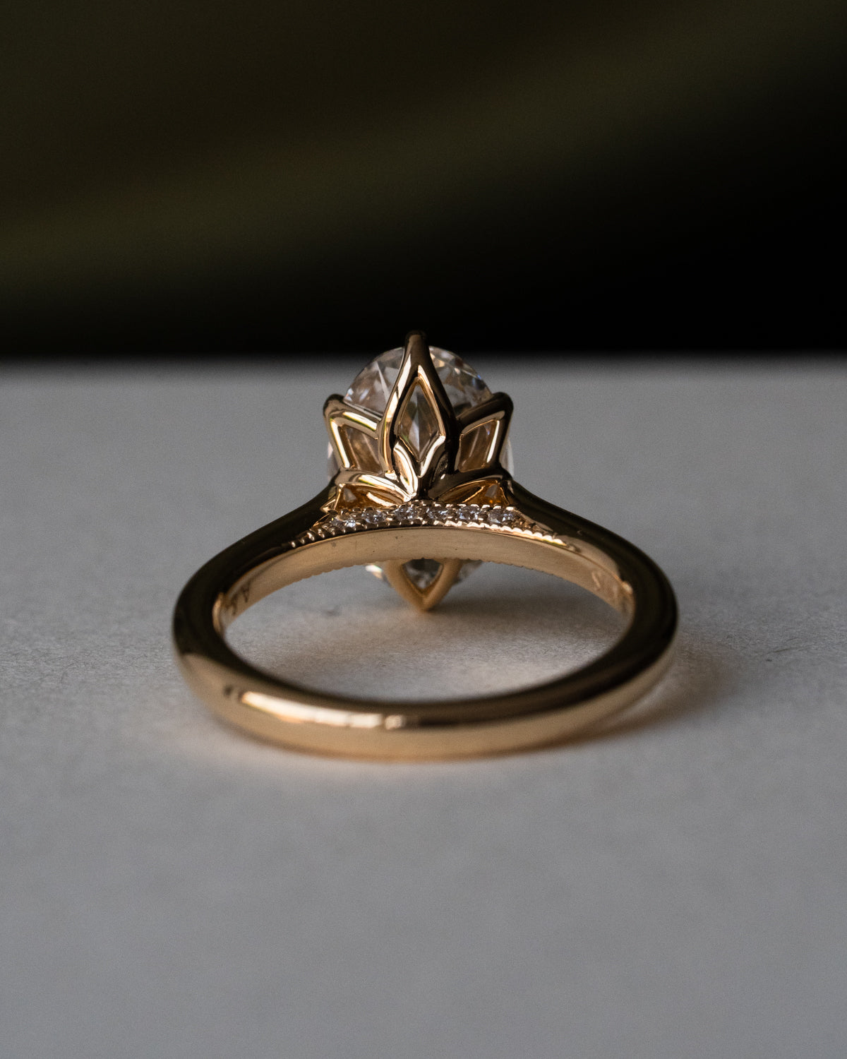 Oval diamond engagement ring in 18k yellow gold with floral prongs and hidden birthstones, back view showing diamond pavé bridge with milgrain detailing