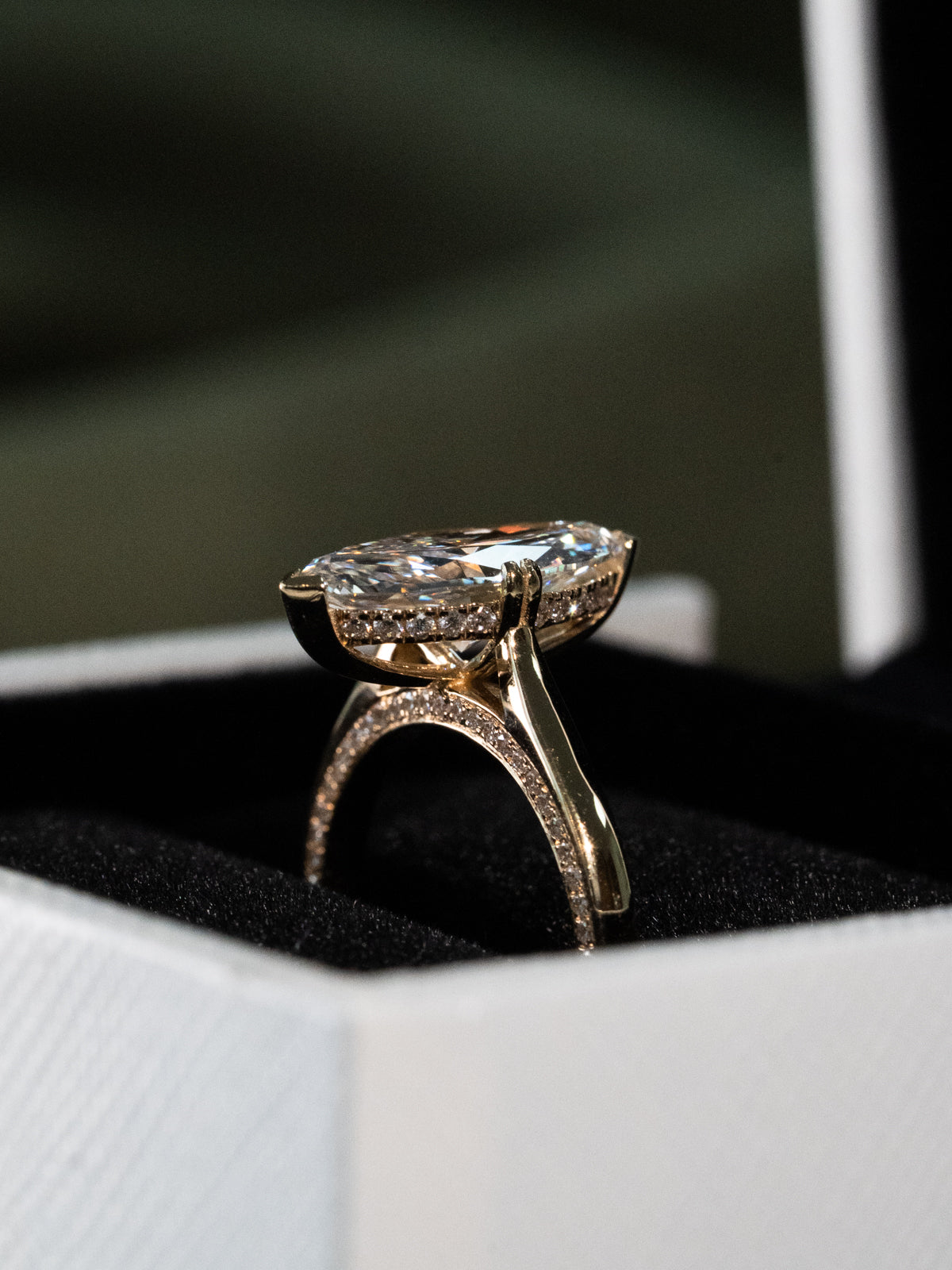 Side view of marquise diamond engagement ring showing cathedral setting and pavé diamond hidden halo, hidden accent stone, hidden side stone band in yellow gold