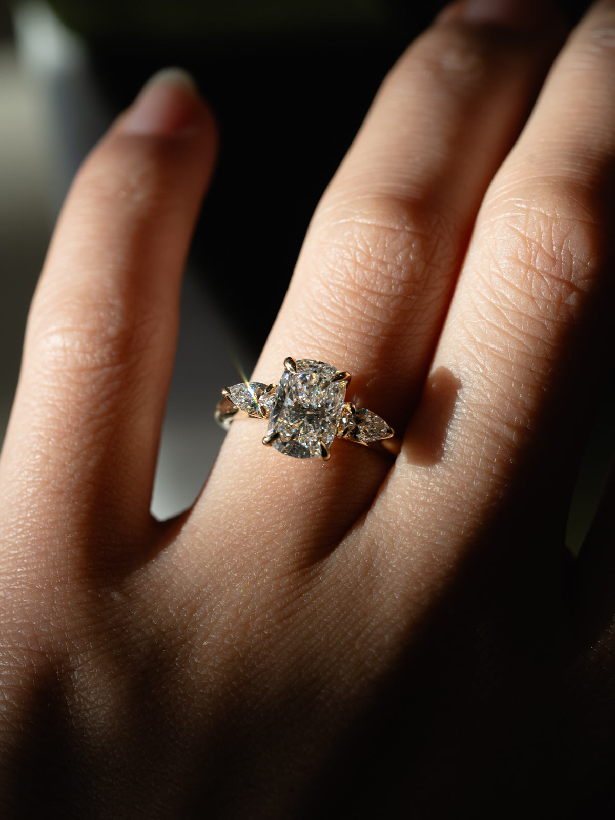 Custom elongated cushion cut diamond engagement ring with natural pear side stones in 18k yellow gold trilogy setting with floral basket and eagle prongs - bespoke engagement ring